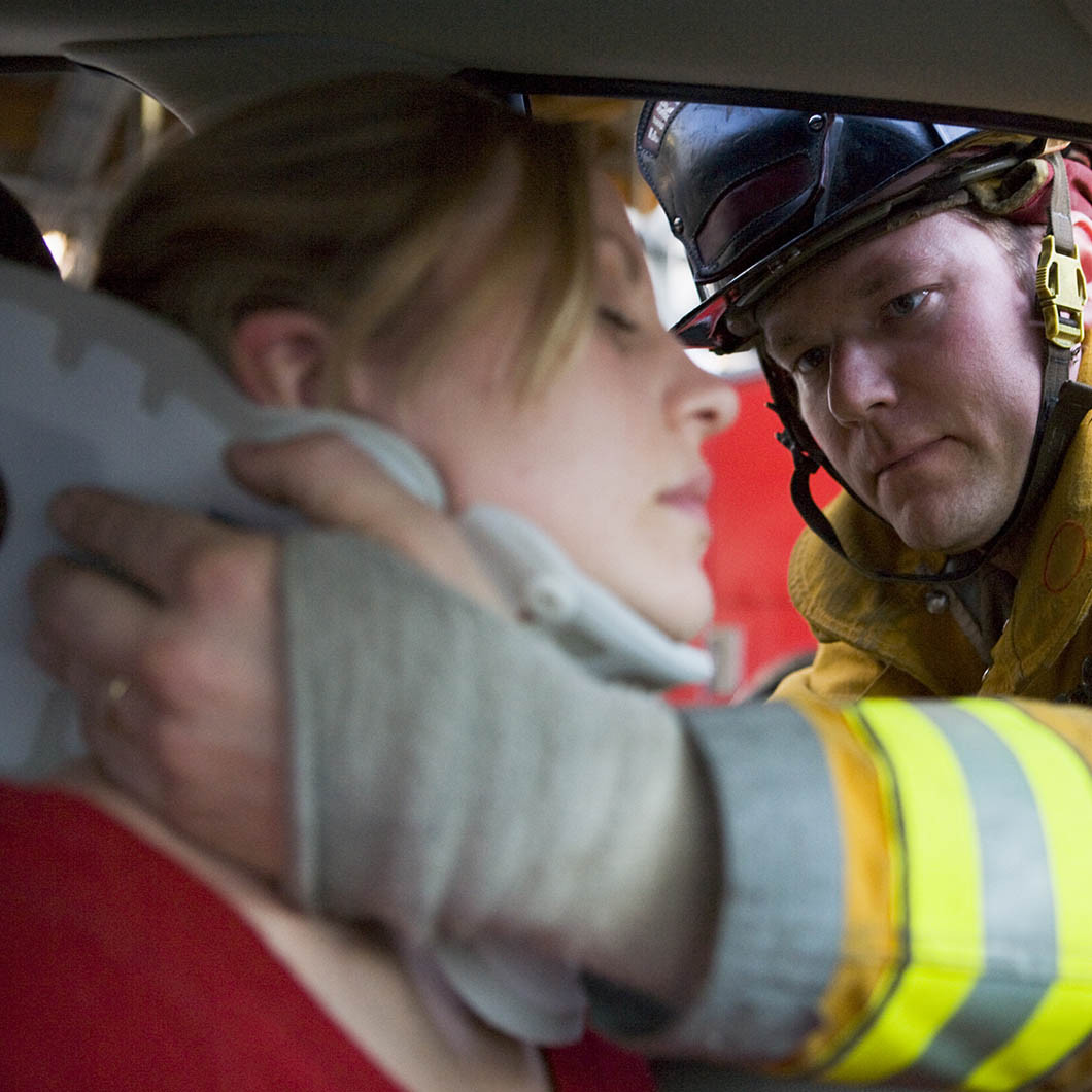 Emergency personnel putting neck brace on woman after car accident